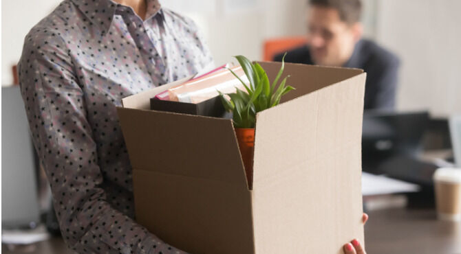 Image of person holding box of office belonging and plant