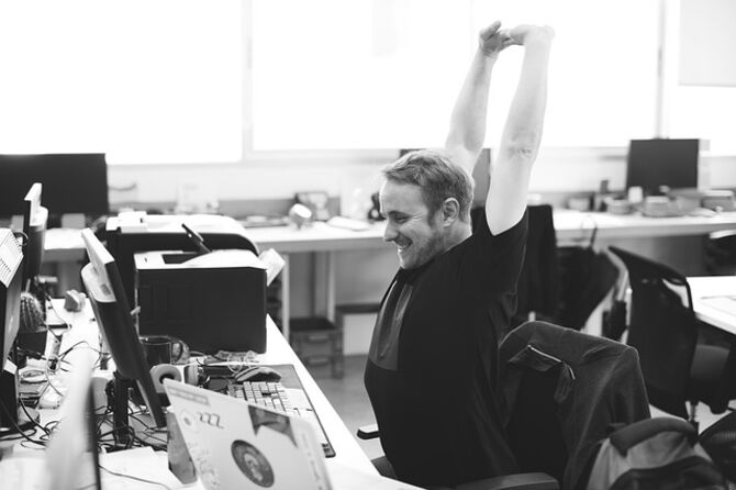 Happy employee stretching at desk