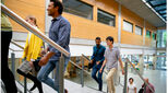 Diverse group of students climb stairs in modern university