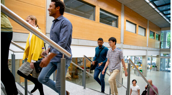 Diverse group of students climb stairs in modern university