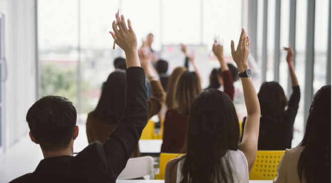 adults with arms raised in support of question