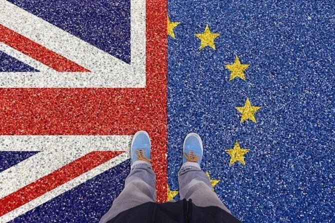 Image of EU and UK and a person standing with a foot on each