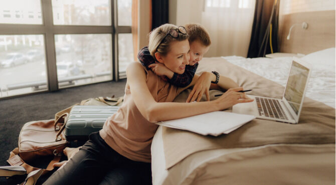 Photo of a businesswoman using her computer in a hotel room, while on business trip with her son