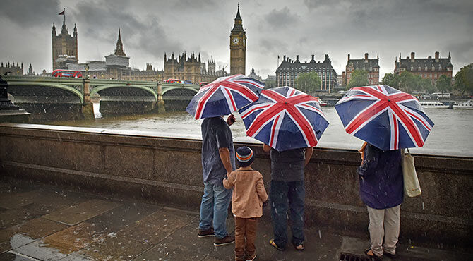 Chubb: first insurers to opt for EU hub in Paris - article illustrated by family with Union Jack umbrellas looking at the UK houses of parliament in London