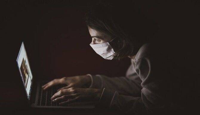 Person with facemask on laptop