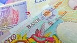 Image of UK currency and small figures sitting on piles of coins