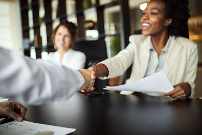 Woman shaking a hand to symbolise a deal sealed