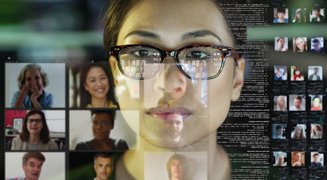 Stock photograph of a professional Asian woman, in her office, looking at a see through display with a team of people making a conference call.