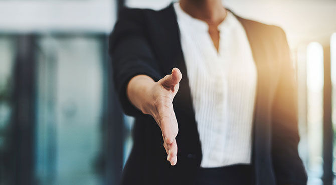 A female boss extends her hand to welcome a newly hired worker