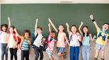 Group of happy diverse children standing in front of whiteboard in classroom