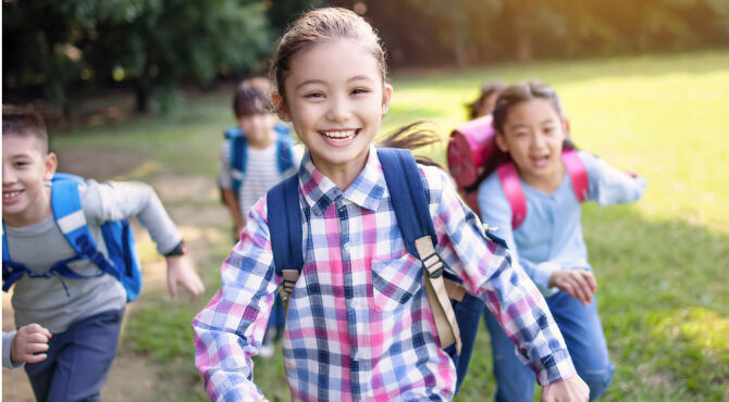 Group of elementary school kids running on the grass