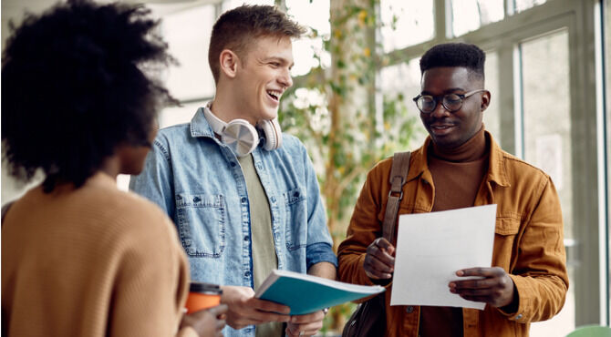 Smiling African American student and his friend analyzing exam results in a hallway at the university