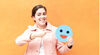A Happy Caucasian woman holding a piece of paper with blue emoji, isolated on orange background. Blue Monday concept