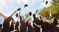 Shot of a group of smiling university students cheering and throwing their caps outside on graduation day