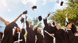 Shot of a group of smiling university students cheering and throwing their caps outside on graduation day