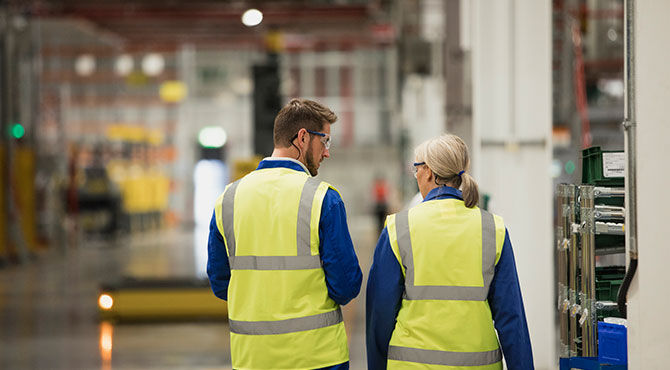 Two workers in a factory in hi-vis jackets