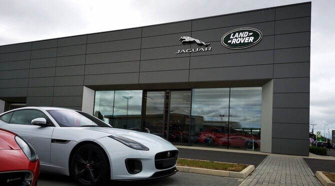 Used Jaguar XJ car for sale outside a Jaguar Land Rover showroom. Jaguar Land Rover Limited is a British multinational automotive company.