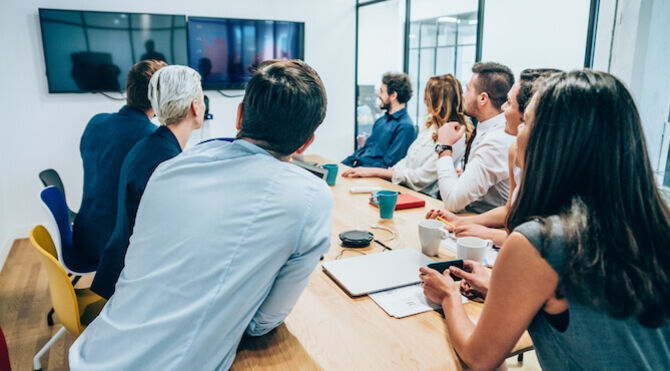 Diverse boardroom leaning in to conversation