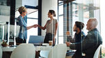 Woman shakes hands with a new recruit while two other workers look on