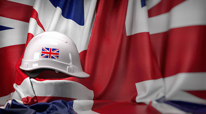 Construction hard hat in front of a union jack flag