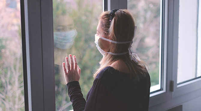 A woman wearing a mask, indoors, alone, socially isolated