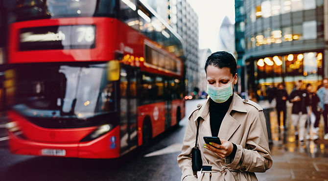 Worker in London on her mobile phone with London bus in background