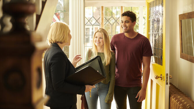 Couple with estate agent looking happy in house