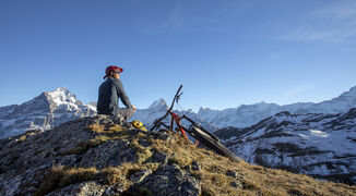 He looks off to sun shining over distant Swiss Alps