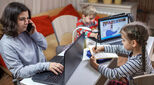 Woman working from home while children do homework in evening