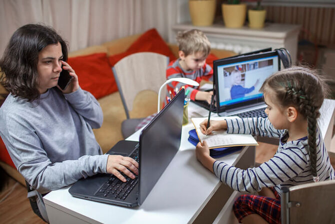 Woman working from home while children do homework in evening