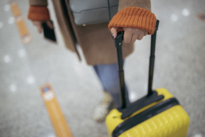 Picture of person waiting with suitcase and passport in hand