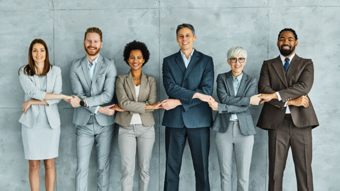 Portrait of a group of young and senior business people holding hands together in the office. Teamwork and success concept