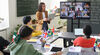 Group of students having international online conference with other students on the screen in the classroom at school