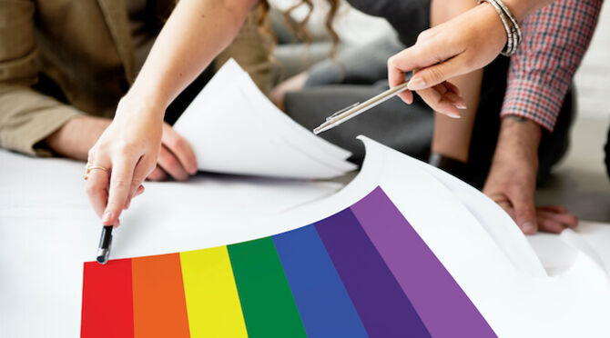 Pride flag on drawing board with people making plans
