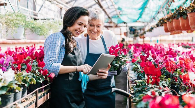 2 women in greenhouse with flowers