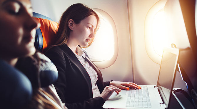 Woman working on a laptop on a plane