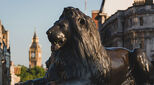 Landseer lions in Trafalgar Square with the Houses of Parliament in the distance, London
