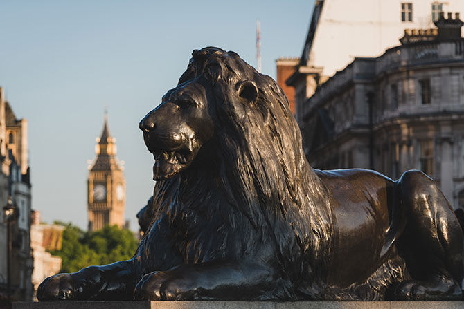 Landseer lions in Trafalgar Square with the Houses of Parliament in the distance, London