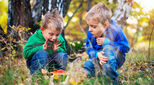 Two preschool children looking delighted in forest setting