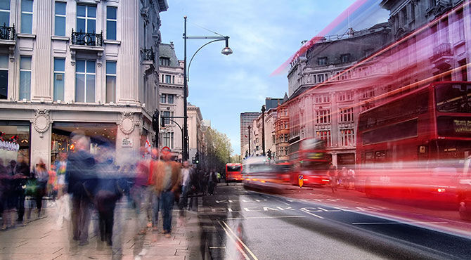 UK red bus with workers walking down the street in front of it