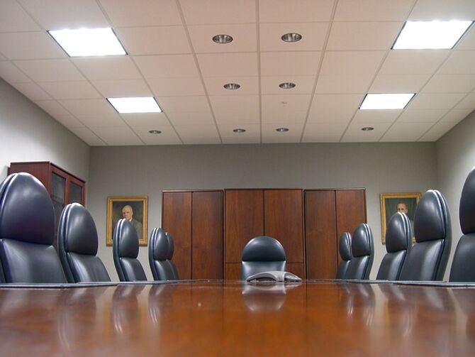 Image of empty board room with images of men in paintings on wall