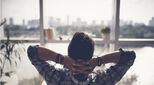 Image of man relaxing in chair looking out on serene city horizon