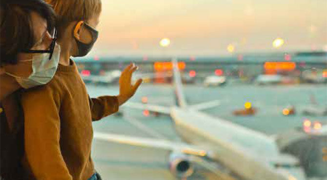 A woman and child look out the window at an airplane, at an airport