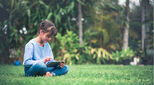 Image of child sitting in tropical garden with iPad looking content and grounded
