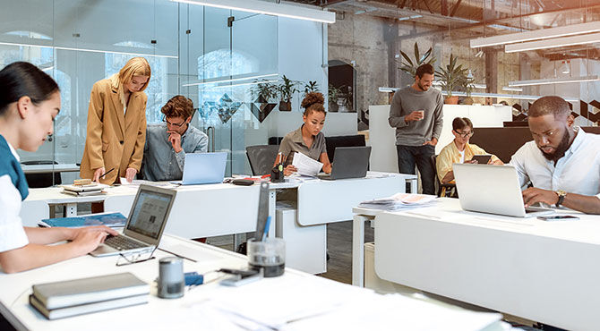 A group of men and women work in an open plan office