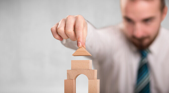 Man building a tower with wooden bricks