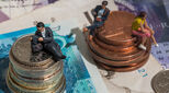Image of coins and models of people sitting on them to represent gender pay gap