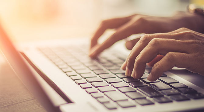 Worker typing on a laptop keyboard