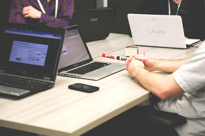 Image of faceless team gathered round laptops