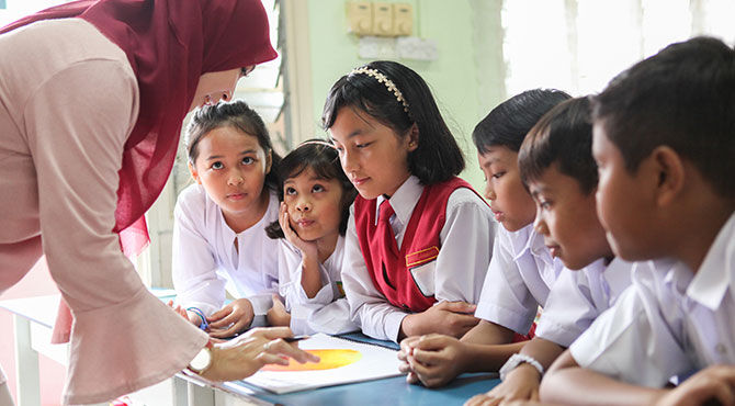A female teacher teaching a group of students in a classroom in Malaysi